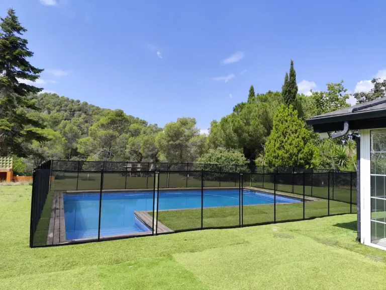 Valla de seguridad para piscina SafetyKids instalada en el jardín de un chalet